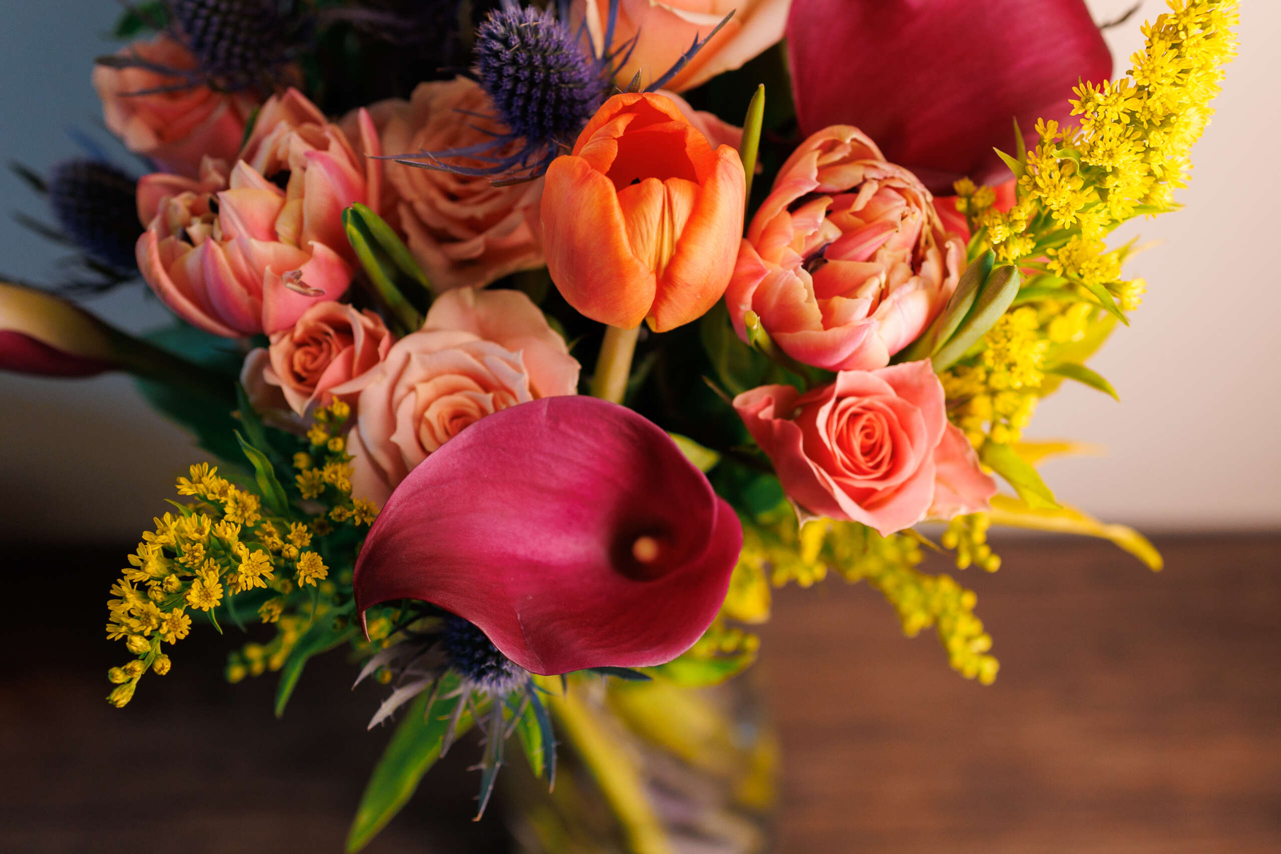 Bright flowers in a vase placed on a wooden table creating a col